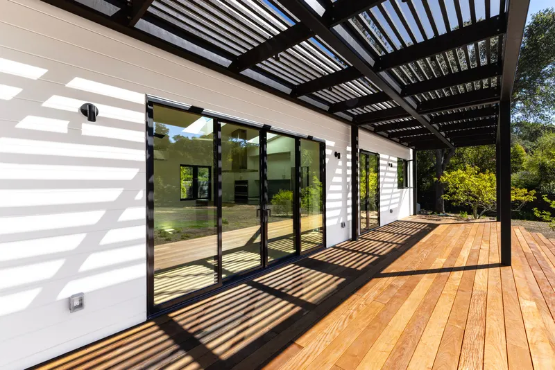 Covered redwood deck with steel pergola and full sliding-glass facade